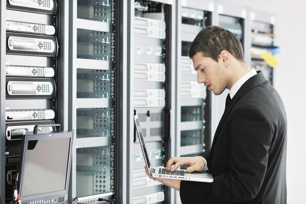 young it engeneer business man with thin modern aluminium laptop in network server room-1 young it engeneer business man with thin modern aluminium laptop in network server room-1